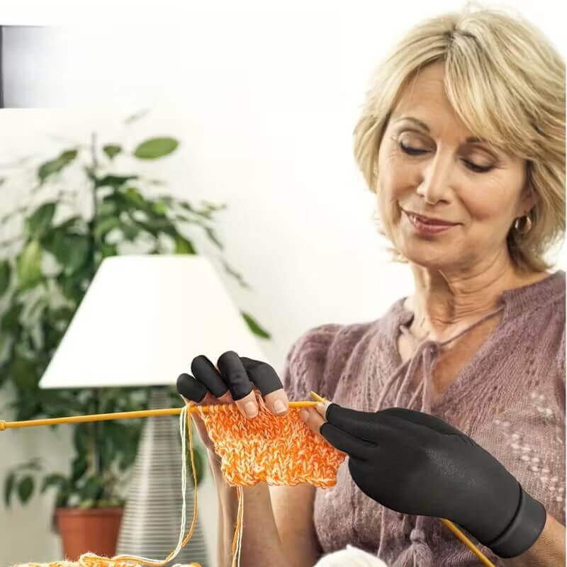 Woman wearing black gloves knitting with orange yarn in a home setting